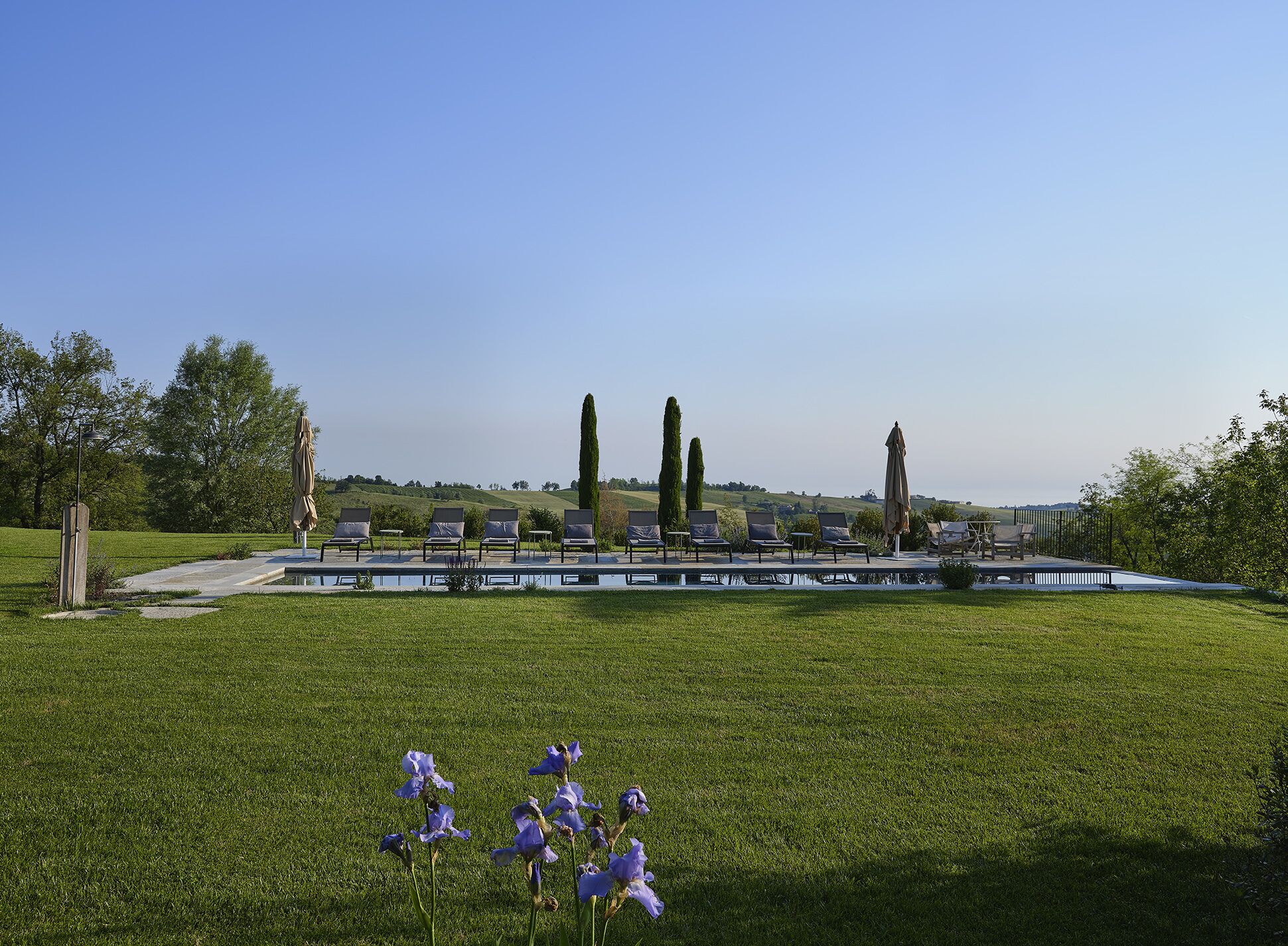 Ein Poolbereich mit Liegestühlen und einer Pergola.