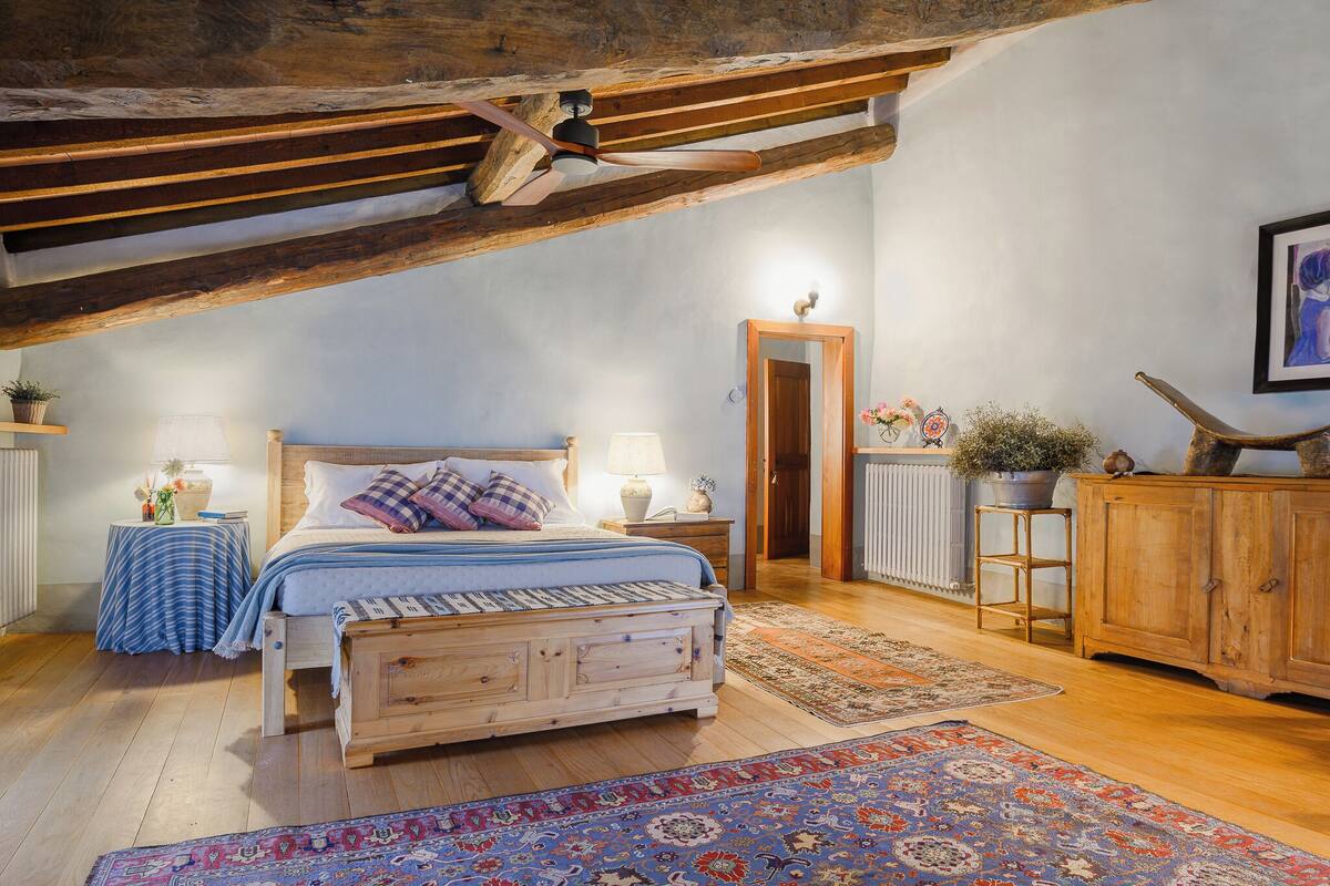 A bedroom with a wooden bed, a nightstand, a dresser, and a radiator.
