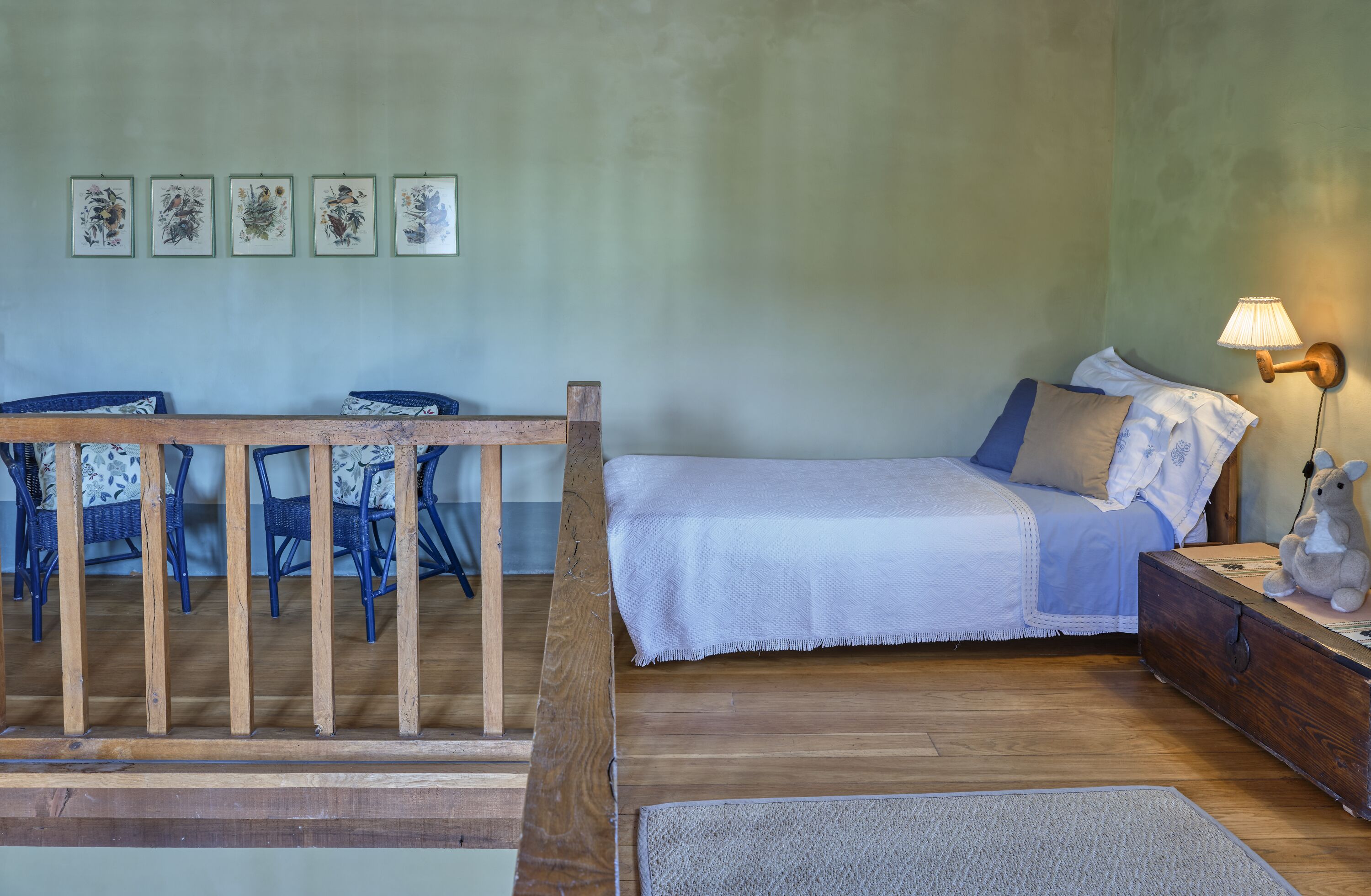 Un dormitorio con cama, mesita de noche, lámpara, silla, mesa y decoración en la pared.