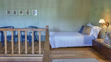 Un dormitorio con cama, mesita de noche, lámpara, silla, mesa y decoración en la pared.