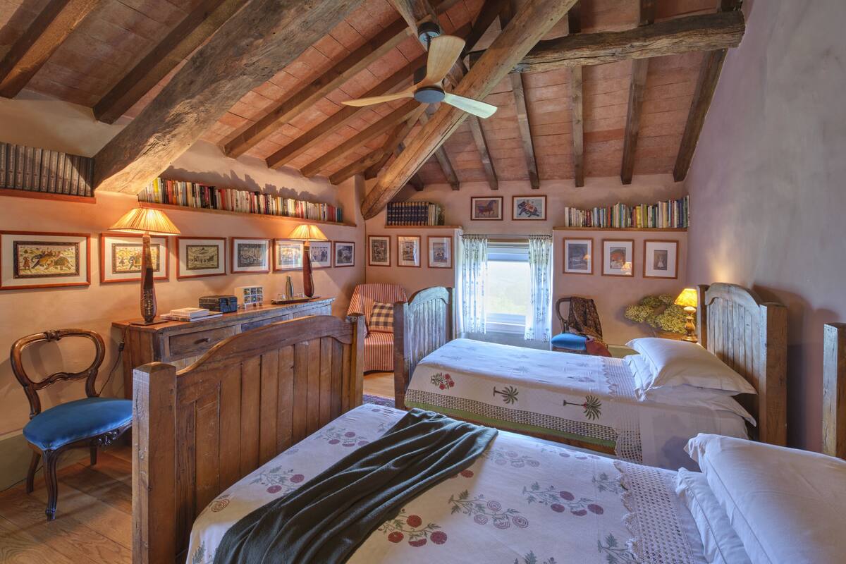 A rustic bedroom with two beds, wooden furniture, and a ceiling fan.
