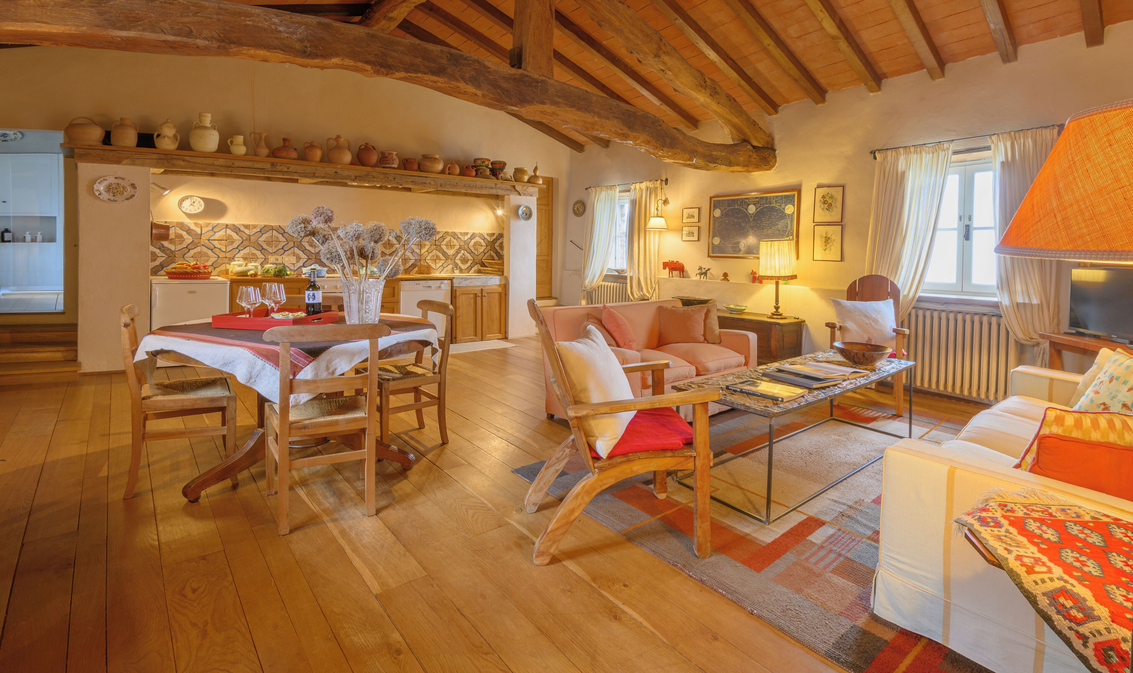 A cozy living area with a wooden dining table, chairs, a sofa, and a TV.