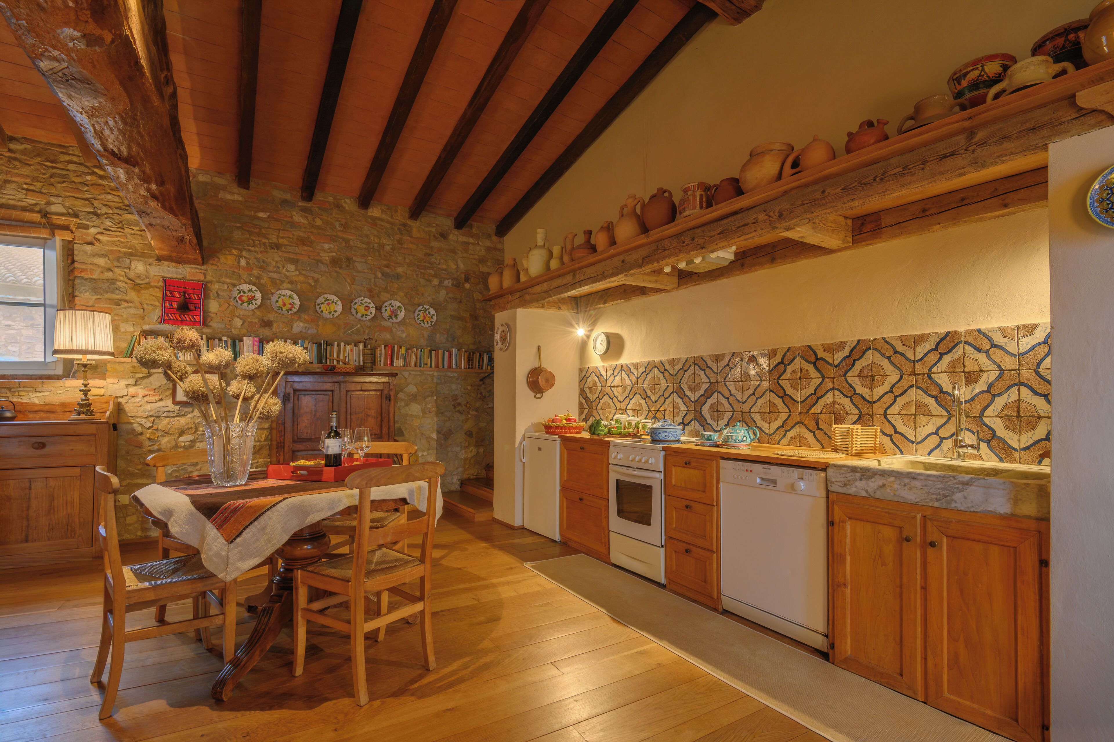 Una cocina rústica con vigas de madera, paredes de piedra y salpicadero de azulejos.
