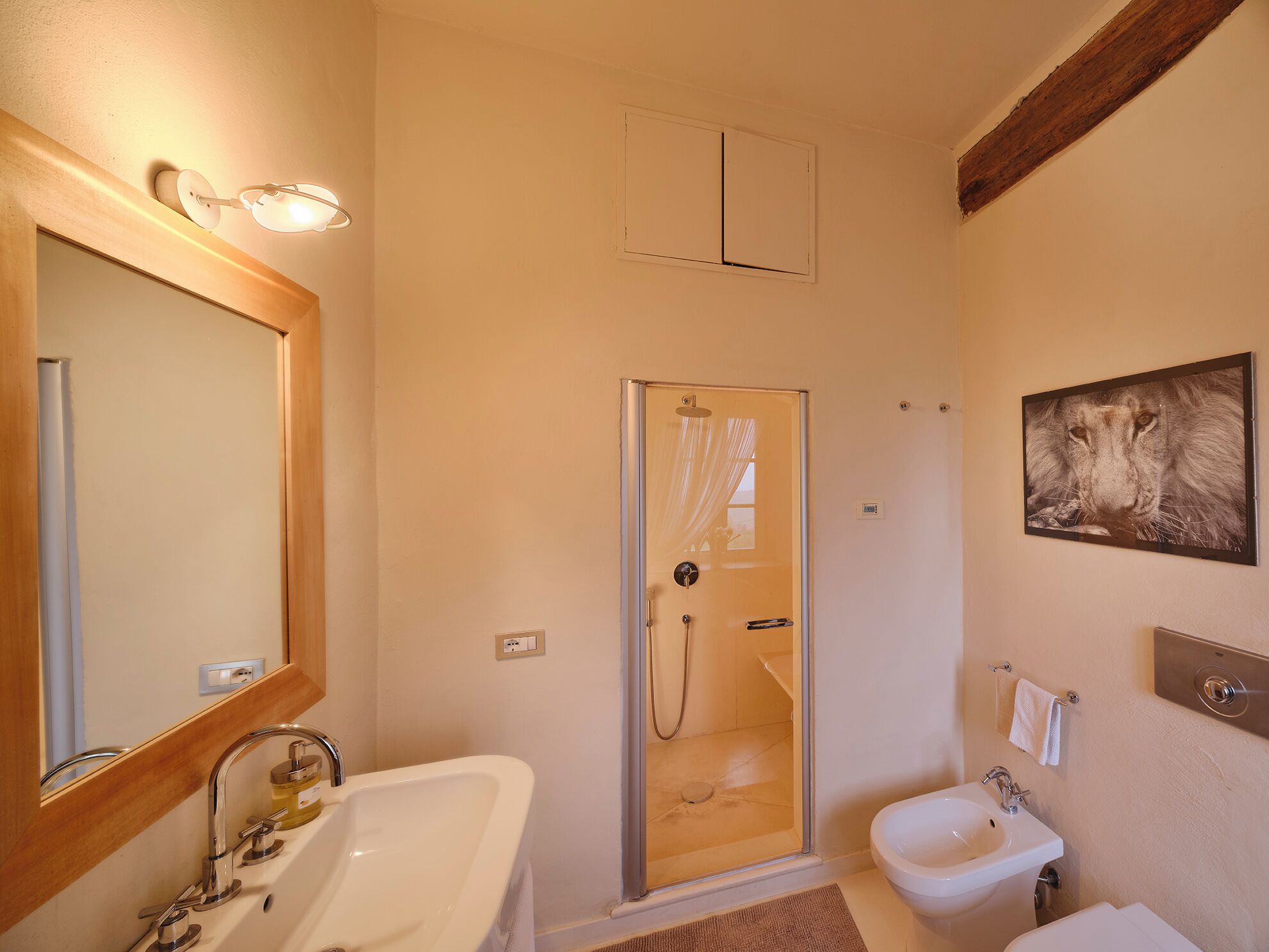 A bathroom with a shower, a sink, a toilet, a mirror, and a wall-mounted light fixture.