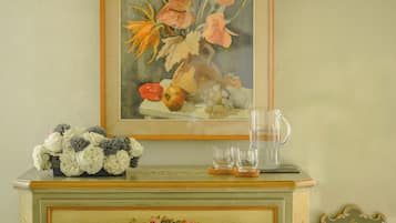A green dresser with floral drawer knobs and a framed painting above it.