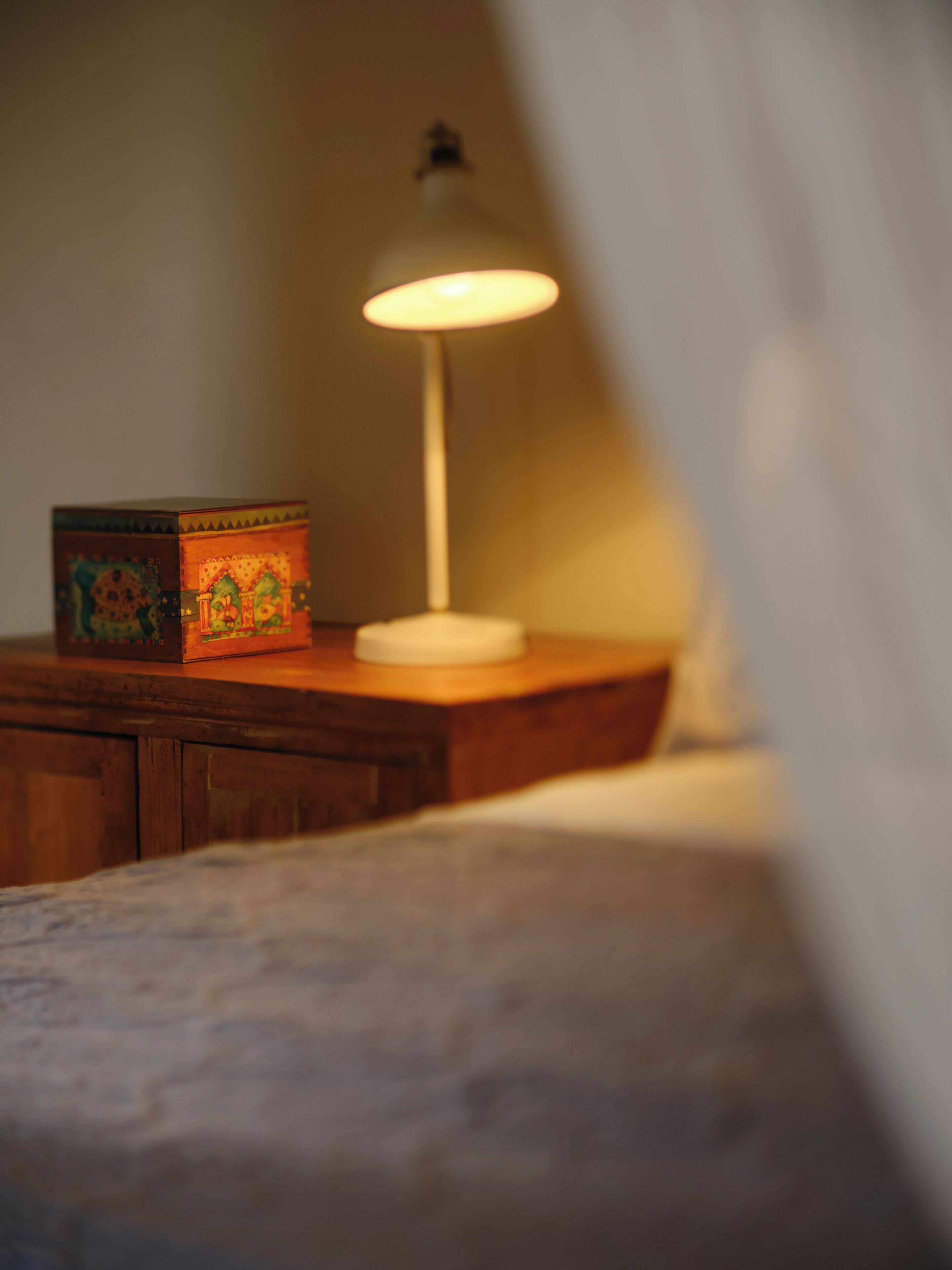 Une table de chevet avec une lampe et une boîte décorative.