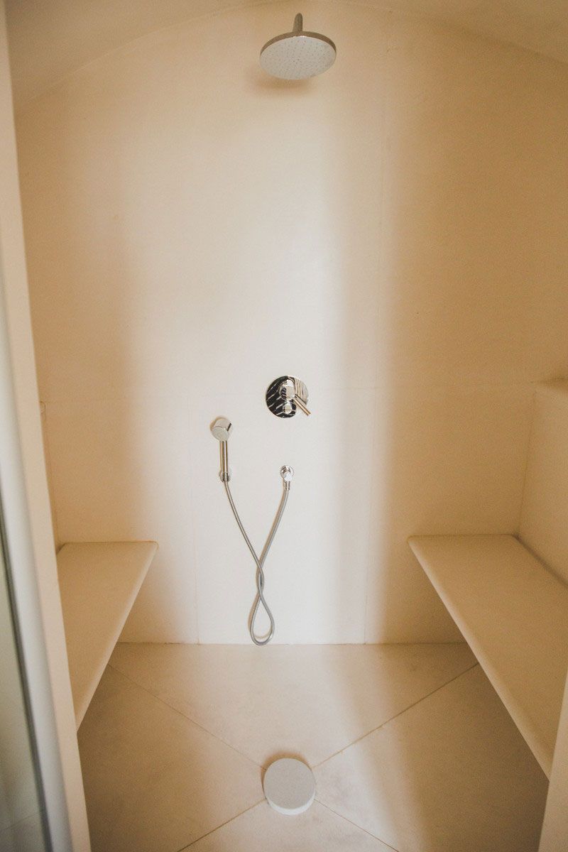 Un espacio de ducha pequeño y cerrado con un cabezal de ducha manual y un grifo instalado en la pared.