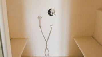 Un espacio de ducha pequeño y cerrado con un cabezal de ducha manual y un grifo instalado en la pared.