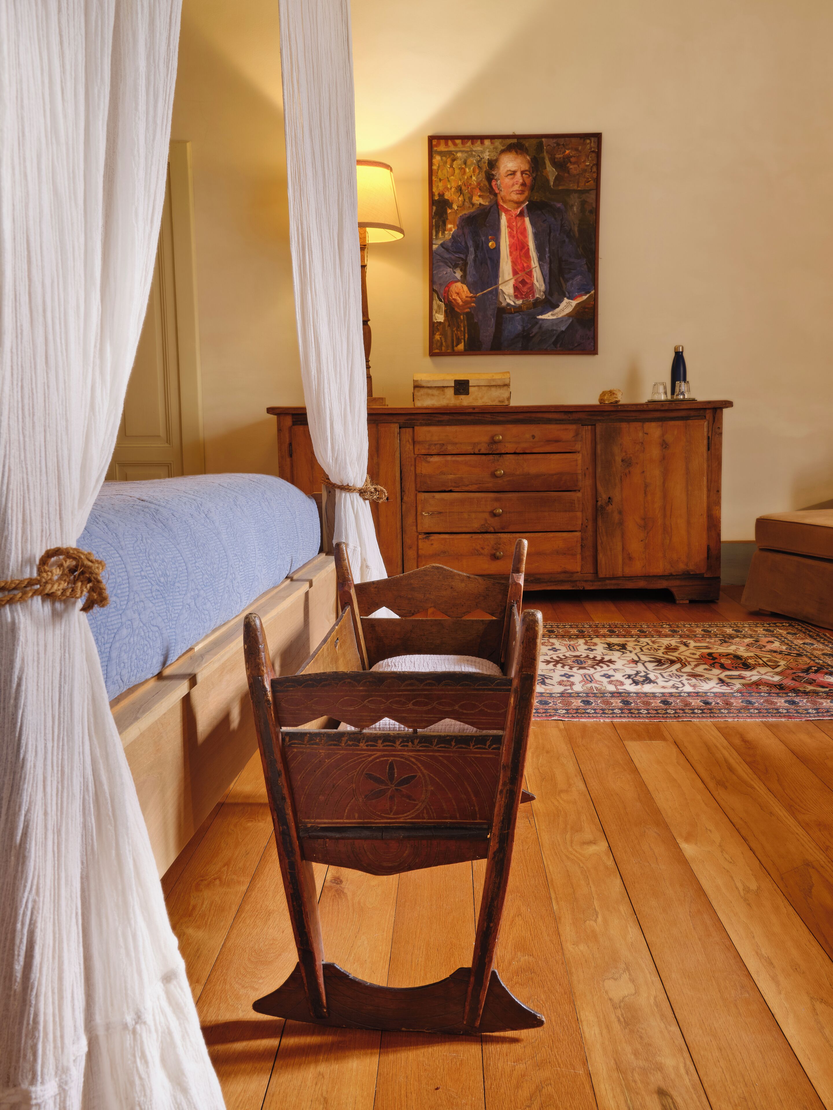A traditional bedroom with a wooden bed, a wooden chair, a wooden dresser, and a painting on the wall.