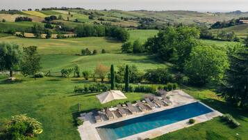 Relax by the serene pool surrounded by lush greenery and rolling hills.