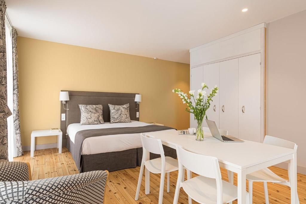 Ein Schlafzimmer mit Bett, Nachttischen, einem Schreibtisch mit Stühlen und einem Kleiderschrank.