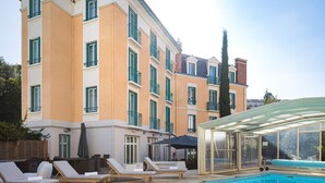 Un hotel con piscina, sillones de descanso y una zona de estar cubierta.