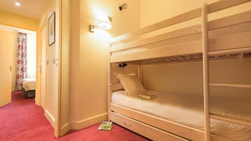 Een slaapkamer met stapelbedden, een rode vloerbedekking, een nachtkastje en een wandlamp.
