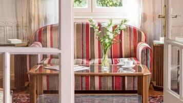 A room with a sofa, a table, and a window with curtains.