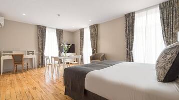 Ein Hotelzimmer mit Bett, Schreibtisch, Stühlen und Vorhängen.