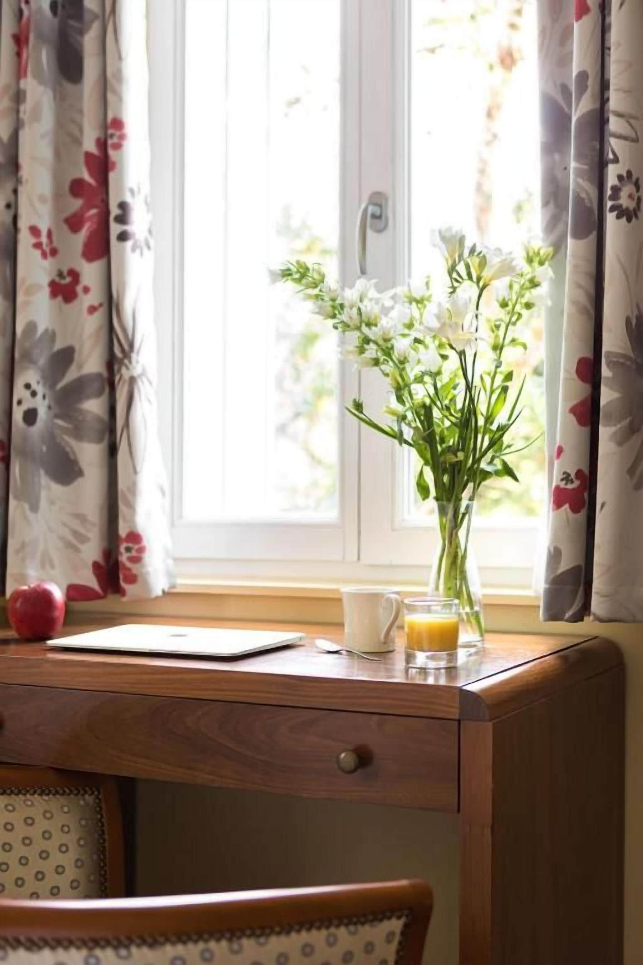 Un bureau en bois avec un ordinateur portable, une tasse et un verre de jus d’orange.