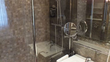 A modern bathroom with a glass-enclosed shower, a white sink, and a large mirror.