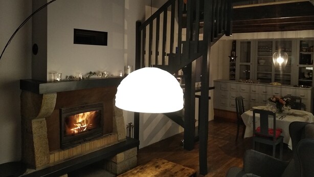 Un salon chaleureux avec une cheminée, un escalier en bois et un coin repas.