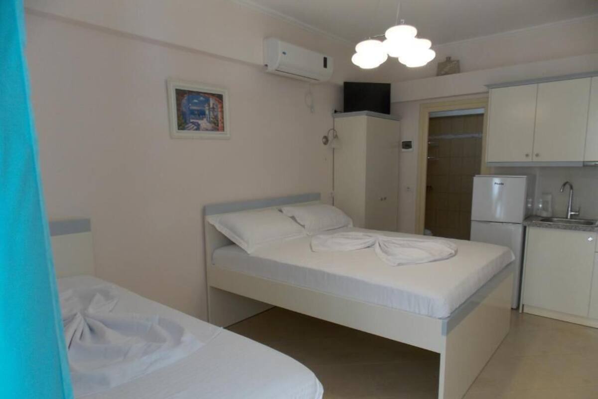 A small, clean room with a single bed, a kitchenette, and a shower area.