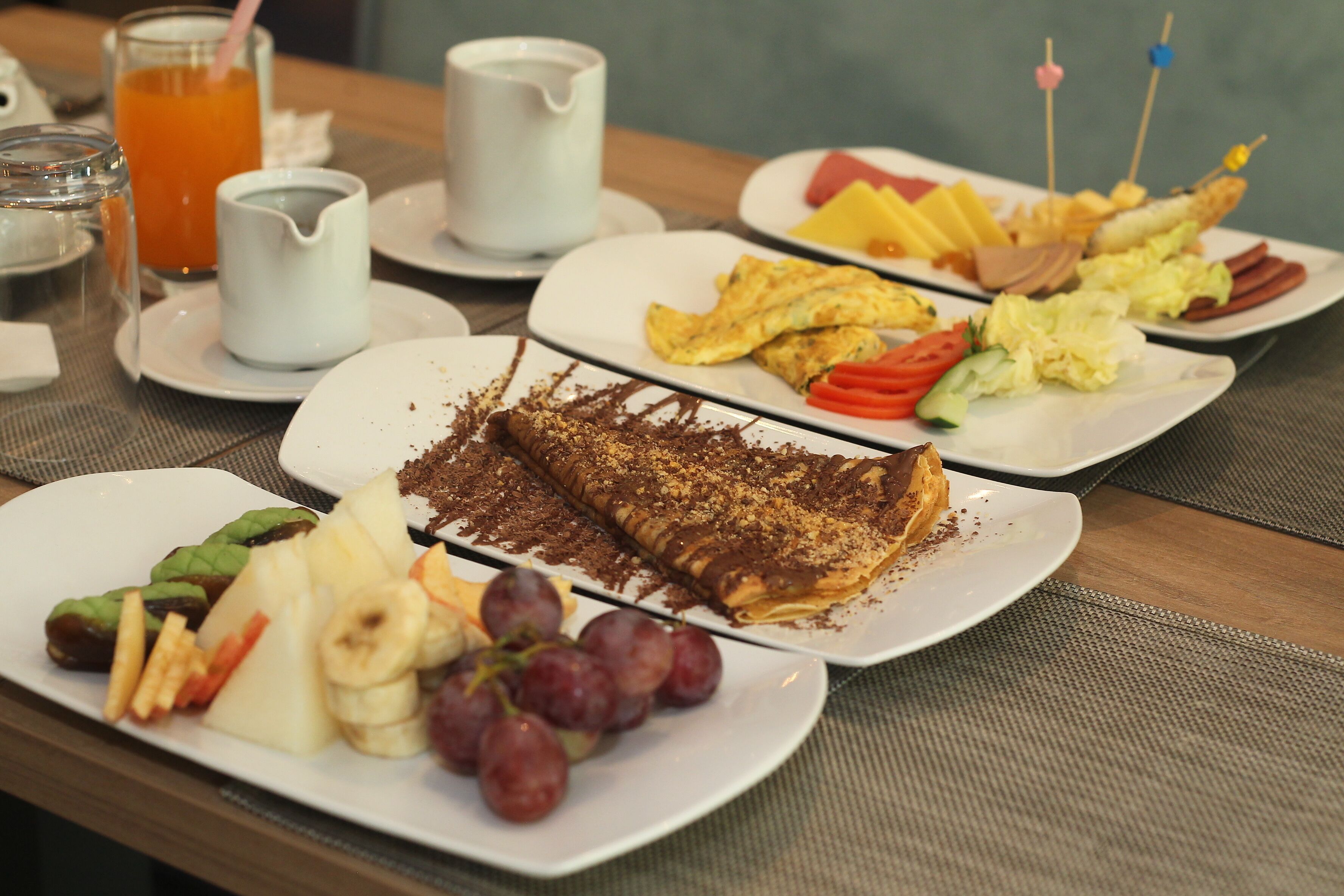 A breakfast buffet with various dishes including eggs, fruits, and a chocolate-topped dessert.
