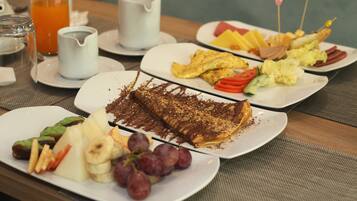 A breakfast buffet with various dishes including eggs, fruits, and a chocolate-topped dessert.