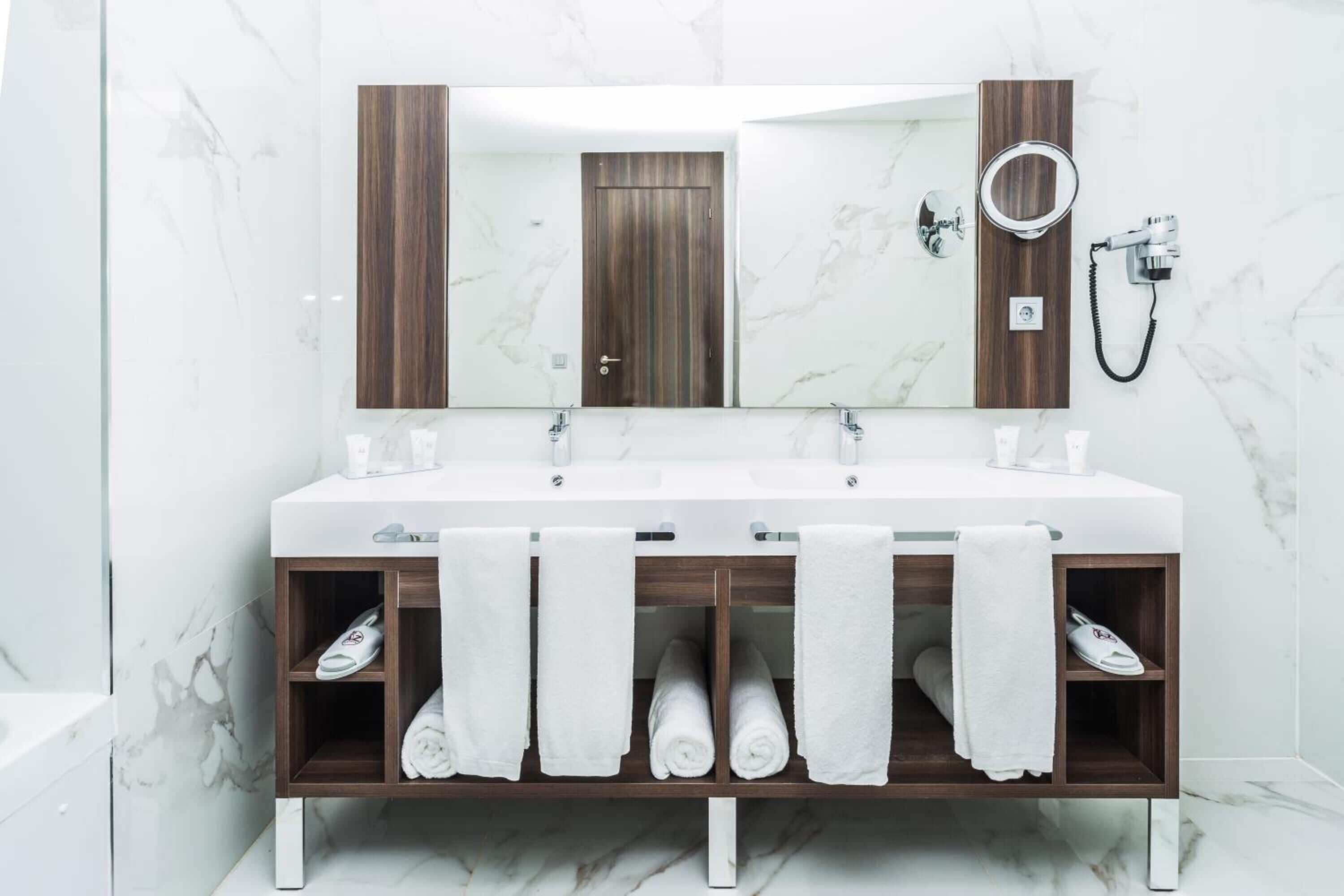 Un baño moderno con tocador doble, un espejo grande y un toallero empotrado.