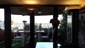 A patio area with outdoor seating, a statue, and a view of the cityscape. - Trastevere 2 (Rome)