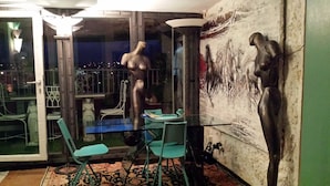 A room with a glass door leading to a balcony, a table with chairs, and a wall with a large painting. - Trastevere 2 (Rome)