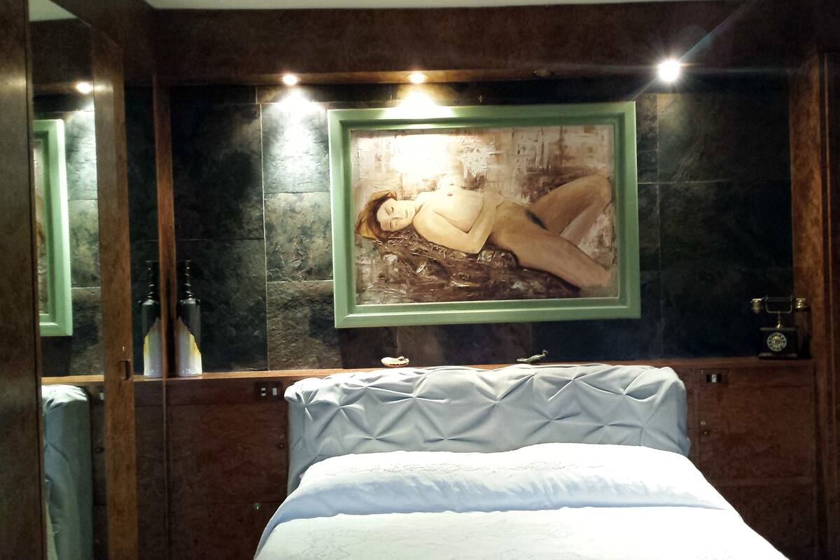 A hotel room with a bed, a framed picture on the wall, and a mirror.