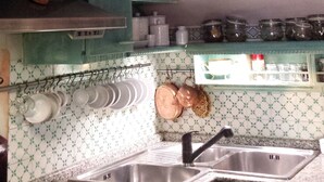 A kitchen with teal cabinets, a gas stove, a sink, and a patterned backsplash. - Trastevere 2 (Rome)