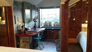 A small, cozy room with a desk, chair, and a window overlooking a garden. - Trastevere 2 (Rome)