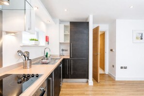 A modern kitchen with a stainless steel stove, a sink, and a wooden cabinet.