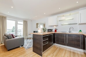 A modern kitchen with dark wood cabinets, a wooden countertop, and a built-in microwave. - Roomspace Apartments -Abbot's Yard (Guildford)