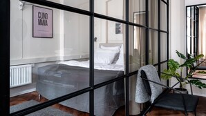 A modern bedroom with a bed, a chair, a potted plant, and a framed picture on the wall. - The Brewer apartments by Daniel&Jacob’s (Copenhagen)