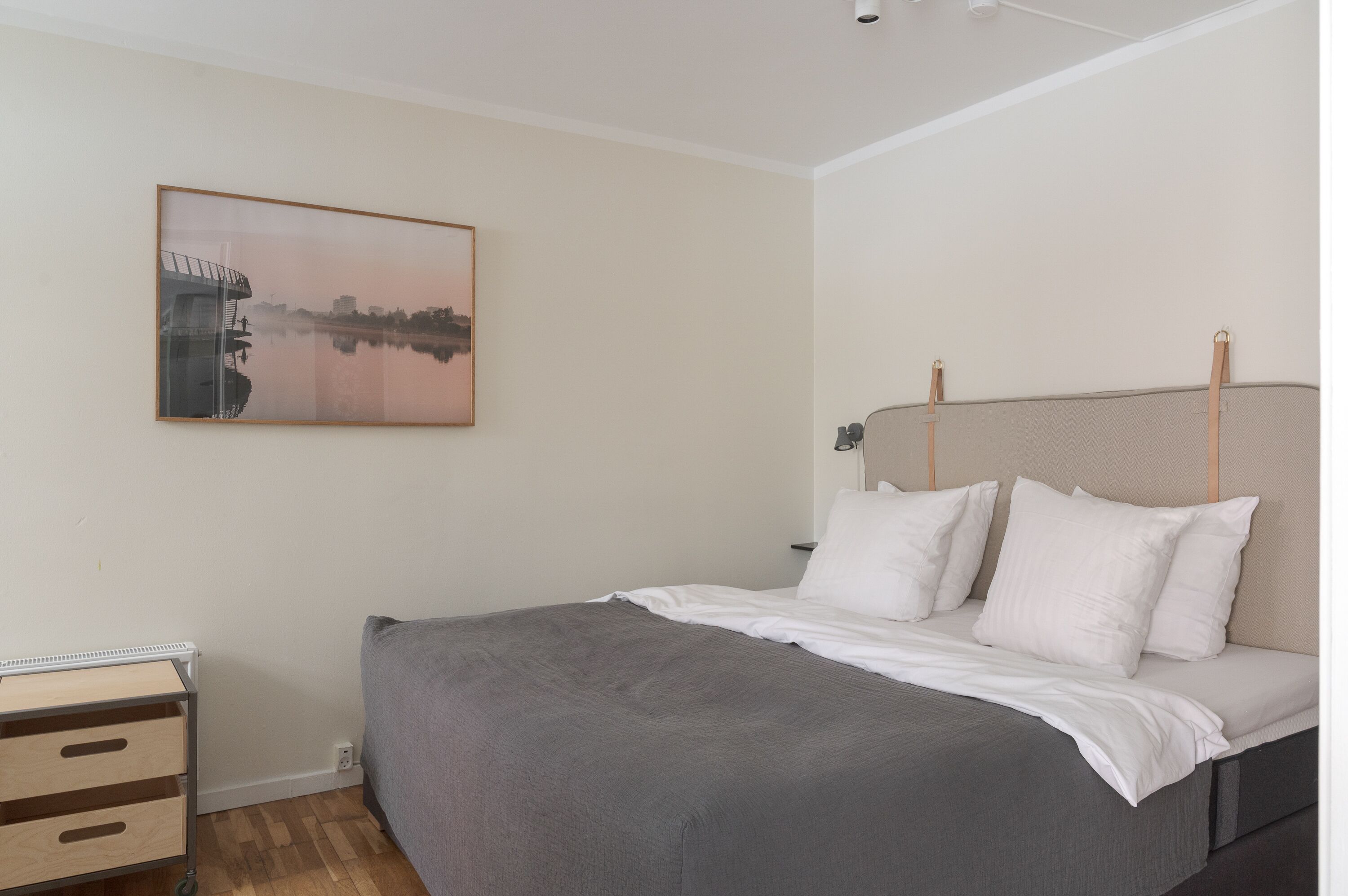 Ein Schlafzimmer mit einem Bett, einem Nachttisch, einem Wandbild und einer Heizung.