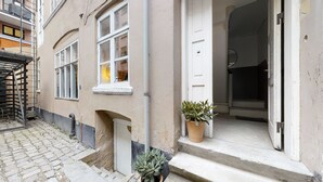 A building with a stone-paved entrance, a metal staircase, and two potted plants on the steps. - The Brewer apartments by Daniel&Jacob’s (Copenhagen)