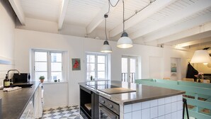 A modern kitchen with a checkered floor, stainless steel appliances, and a teal accent wall.