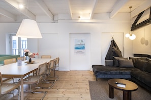 En moderne stue med sofa, sofabord og spiseplads med stole og bord.