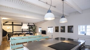 A modern kitchen with a large island, pendant lights, and a seating area with a sofa and chairs.