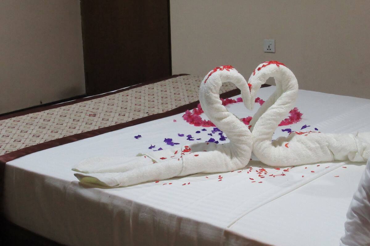 A bed with a white sheet and a decorative swan arrangement made of towels.