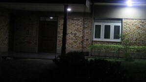 A building at night with a lit street lamp, a brick wall, and a window with a metal grill. - Kalamatiya Bird Sanctuary (Kalametiya)