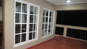 A room with two large windows, a black screen on the wall, and a red-tiled floor. - Kalamatiya Bird Sanctuary (Kalametiya)