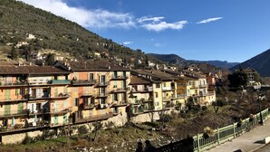 A row of colorful buildings with balconies, set against a backdrop of hills and a clear sky. - Hostellerie du Pont Vieux (Sospel)