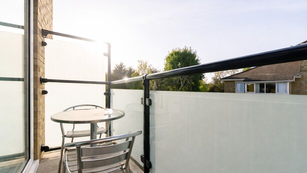 Ein Balkon mit Glastür, einem runden Tisch und einem Metallstuhl.