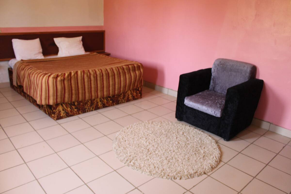 A bedroom with a bed, a chair, and a rug.
