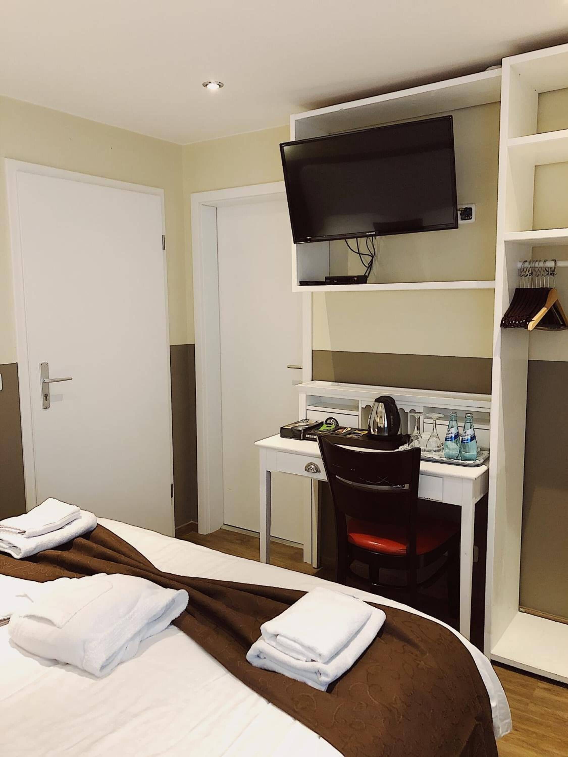 Une chambre d’hôtel comprenant un lit, un bureau avec une chaise, une télévision et une armoire.