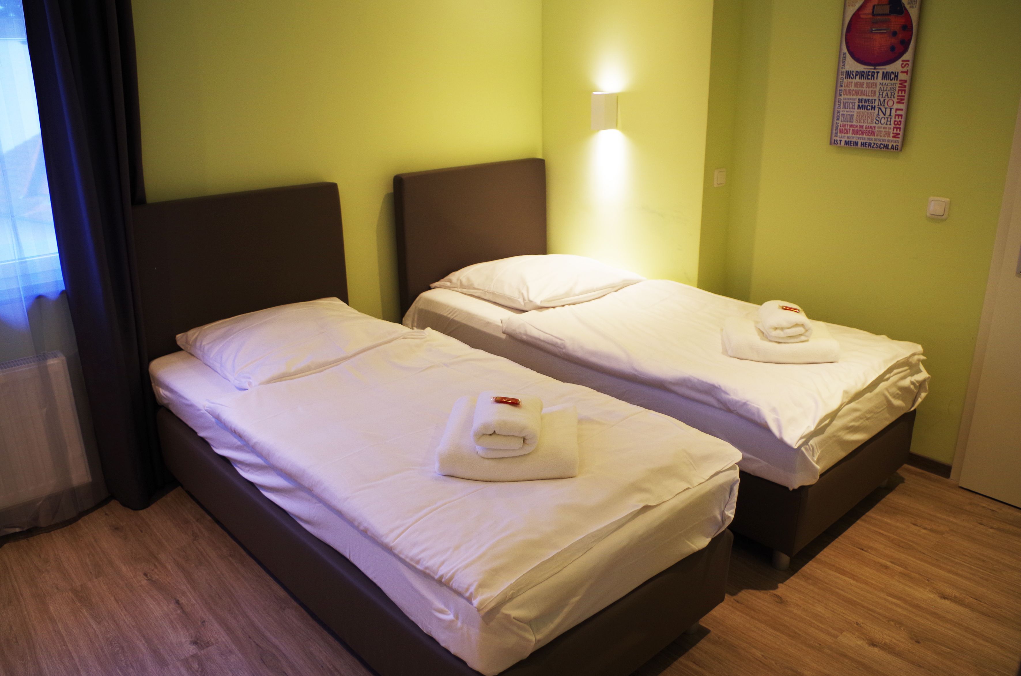 Habitación de hotel con dos camas, cada una con ropa blanca y una toalla encima.