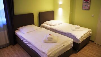 Habitación de hotel con dos camas, cada una con ropa blanca y una toalla encima.