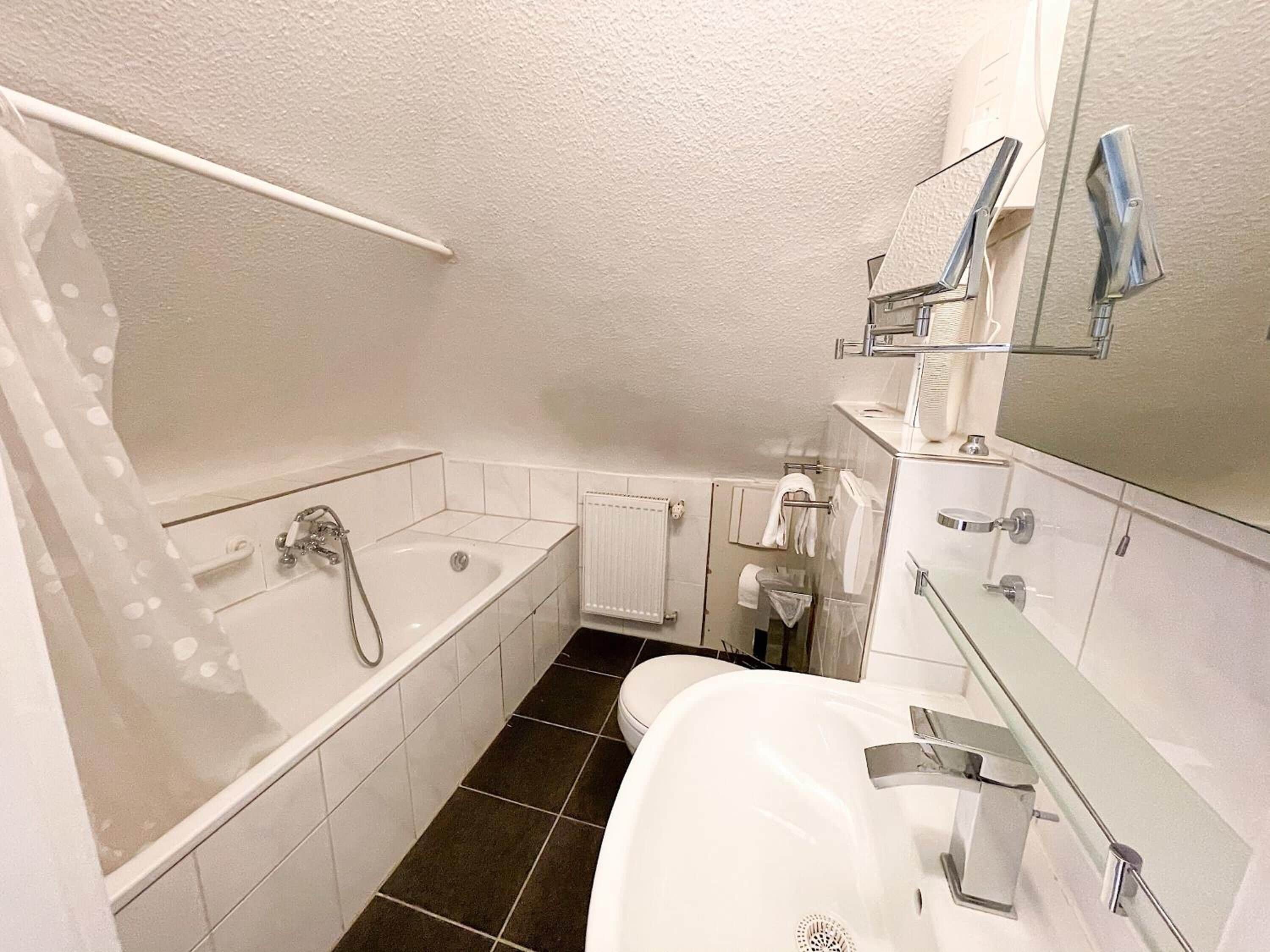 A modern bathroom with a bathtub, a shower, a toilet, and a sink.
