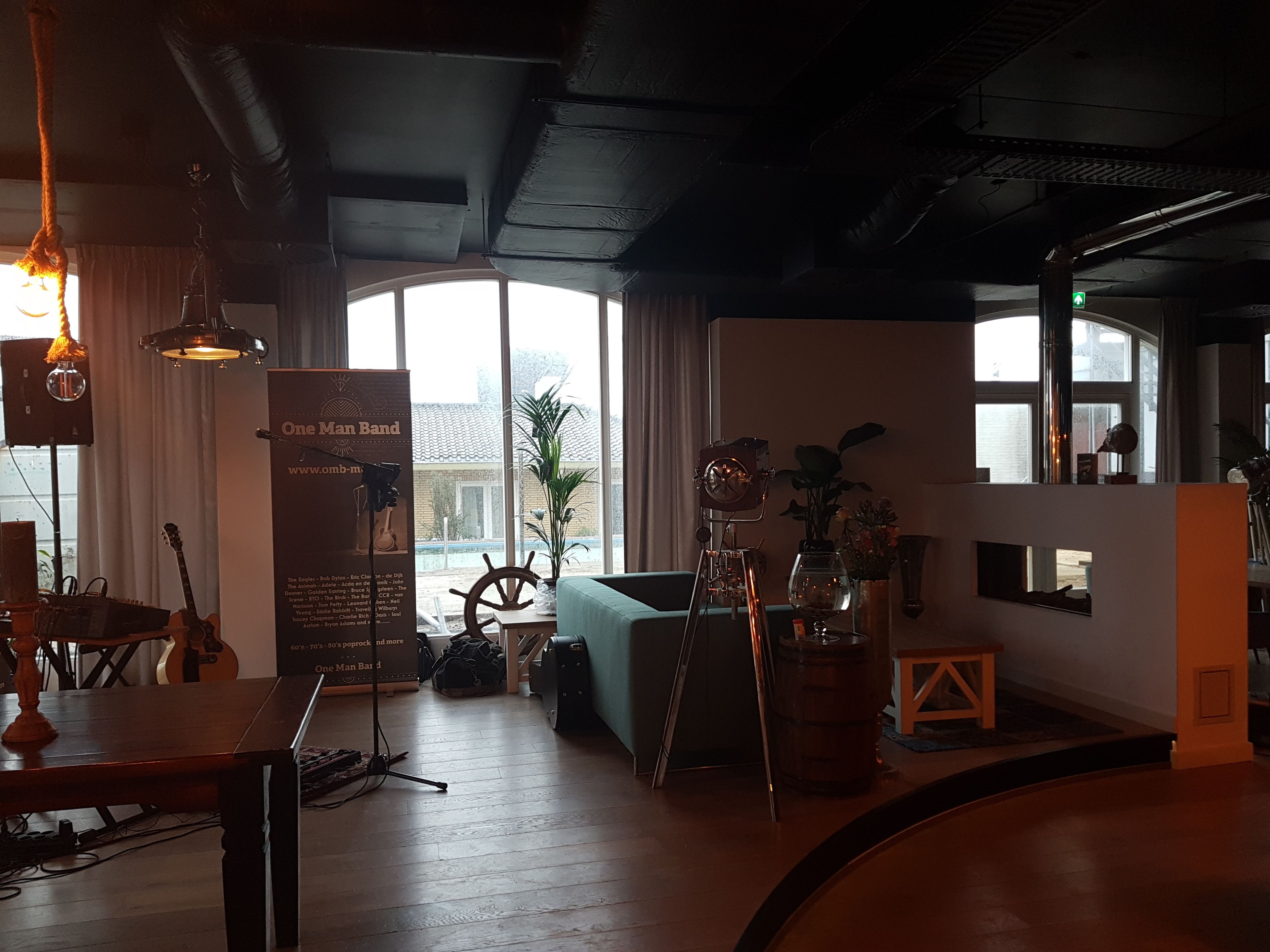 A cozy room with a wooden table, a guitar, a plant, and a vintage clock.